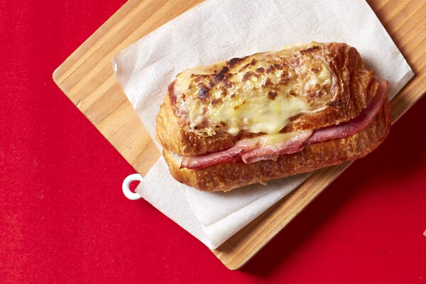 Croque Monsieur on Croissant Baguette, P170. This flaky butter croissant baguette is filled with slow-roasted honey ham, Fontina and Emmental cheese, then topped with béchamel sauce and grated cheese. It's best eaten warm.